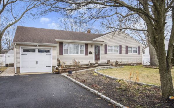 Single-story beige house with attached white garage and dark shutters, front walkway and steps, leafless trees in yard.